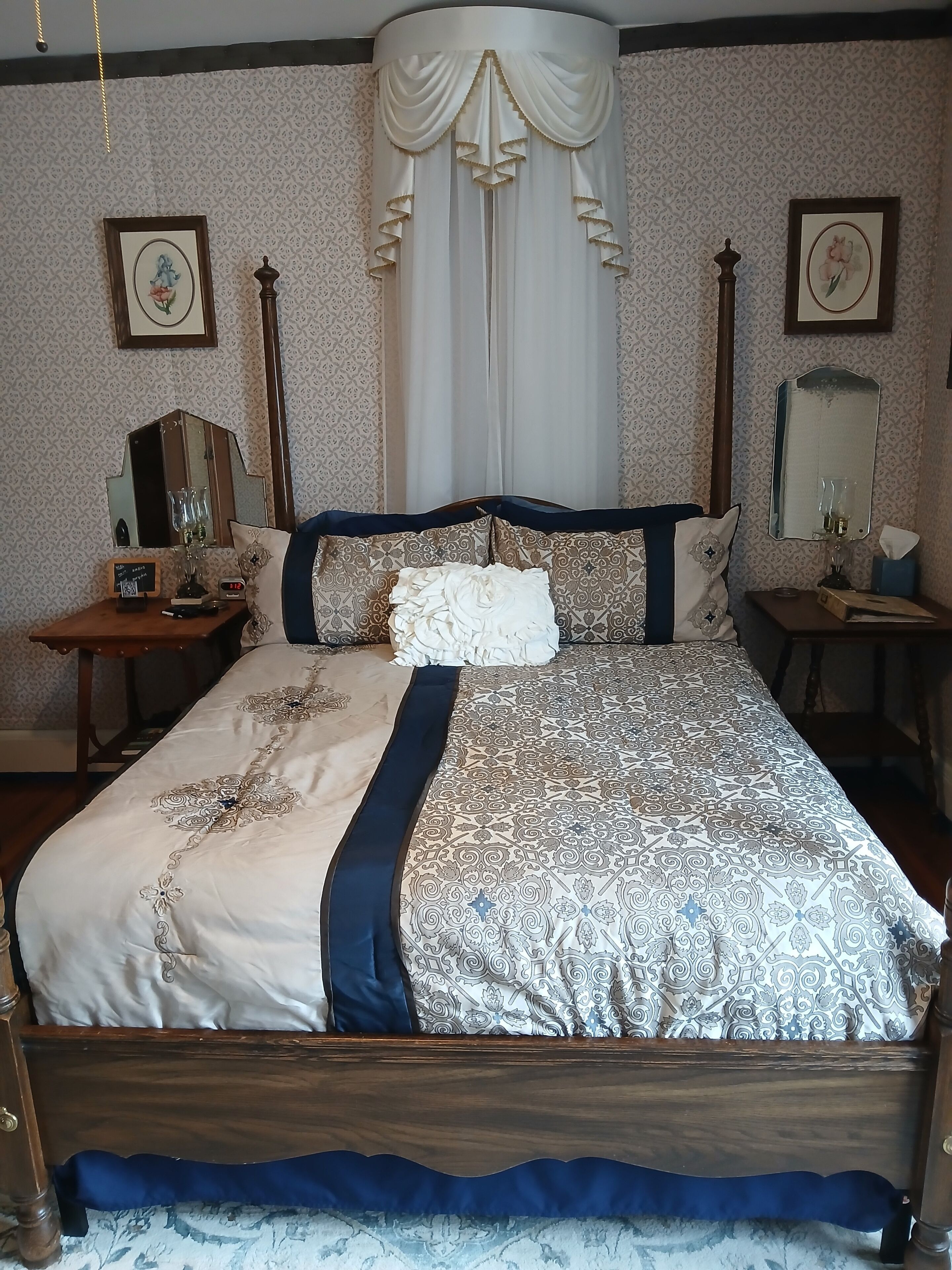 A traditional bedroom with a large bed, a nightstand, a dresser, and a mirror.