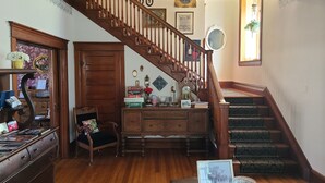 A grand staircase with wooden railings and a chandelier, leading to a landing with a mirror and framed pictures. - The Bissing House (Hays)