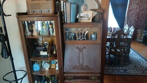 A wooden cabinet with glass doors, containing various decorative items and a framed picture. - The Bissing House (Hays)