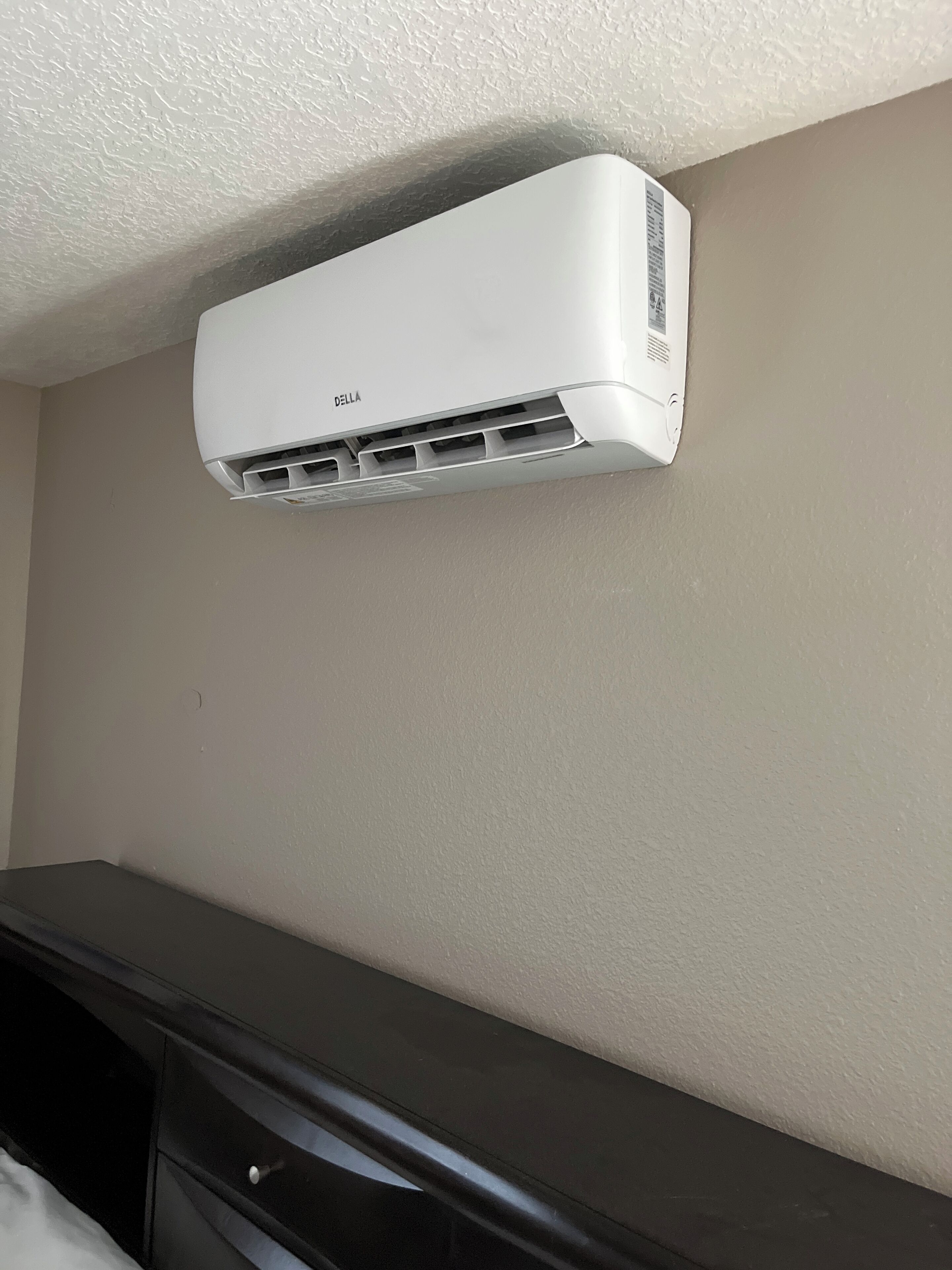 Un equipo de aire acondicionado blanco instalado en la pared, con la marca DELLA.