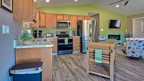 Una cocina moderna con armarios de madera, electrodomésticos de acero inoxidable y un comedor con mesa y sillas de madera.