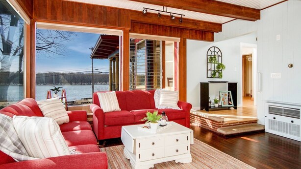 A spacious living room with a red sofa, a white coffee table, and a fireplace. - Great River Road - Victorian Historic Home (1898) (Fountain City)