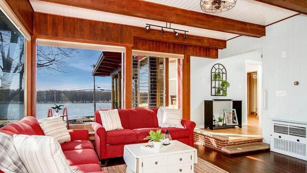 Un salon spacieux avec un canapé rouge, une table basse blanche et une cheminée.