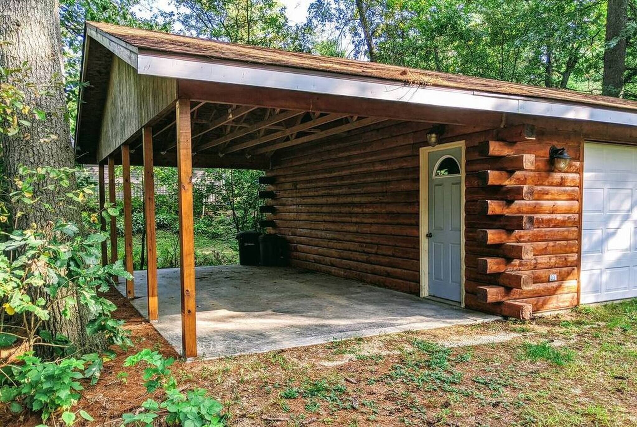 A log cabin with a covered porch, a door, and a garage.