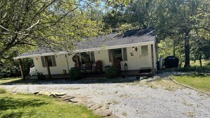 A single-story house with a porch, a covered outdoor grill, and a gravel driveway. - Cozy Lake House: Ark Encounter, Kincaid Lake, KY- Fishing, Scenic Get-Away (Falmouth)