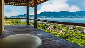 A wooden deck with a view of a mountainous landscape and a body of water. - Casa Tiffany - Ilhabela (Ilhabela)