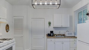A modern kitchen with white cabinets, a gas stove, a microwave, and a coffee maker. - Stunning Memphis` Neighborhood-Guest House Retreat (Memphis)