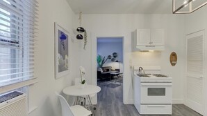 A modern kitchen with white cabinetry, a gas stove, and a white dining area with a table and chairs. - Stunning Memphis` Neighborhood-Guest House Retreat (Memphis)