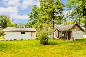 A small, single-story building with a sloped roof, a front porch, and a small front yard.