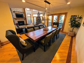 Un coin repas avec une table en bois, des chaises, un sapin de Noël et une cheminée.