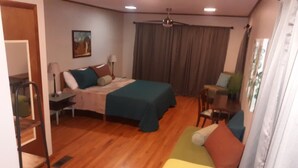 Une chambre avec deux lits, un bureau, une chaise et un ventilateur de plafond.