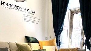Een moderne woonkamer met een glazen salontafel, een bank met gestreepte kussens en een leren vloerkleed.