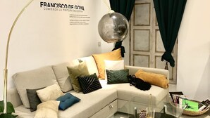 Een moderne woonkamer met een hoekbank, een glazen salontafel en een vloerlamp.