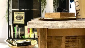 Een houten tafel met een glazen vaas, een lijst met foto en een mand vol tijdschriften.