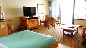 Una habitación de hotel con cama, televisor, escritorio y silla.