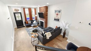 A modern living room with a fireplace, a sofa set, and a dining area. - ★ HostWise Stays ★ Spacious Stay in Prime Location | Theater & Patio (Pittsburgh)