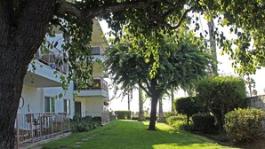 Une cour avec une pelouse bien entretenue, un chemin en pierre et un bâtiment doté d’un balcon.