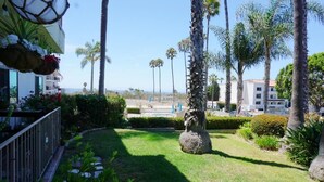 Un jardin bien entretenu, agrémenté de palmiers, d’une statue et offrant une vue dégagée sur l’océan.