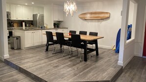 Une cuisine moderne avec des meubles blancs, des appareils en acier inoxydable et une table à manger en bois, assortie de chaises noires.