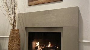 Une cheminée au design moderne, un grand tableau accroché au-dessus et un vase décoratif posé sur le sol.