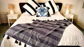 A neatly made bed with a striped blanket, two bedside tables with lamps, and a decorative pillow.