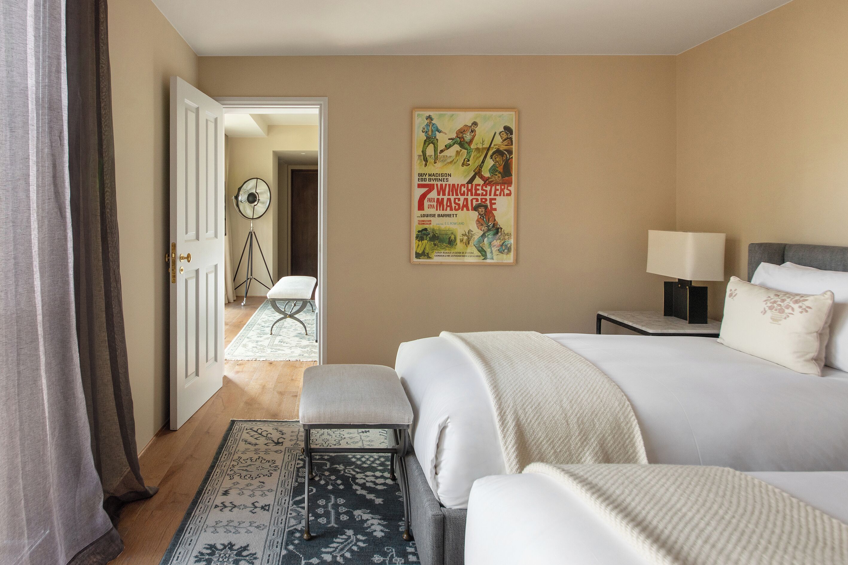 Una habitación de hotel con cama, mesita de noche, lámpara y un cartel en la pared.