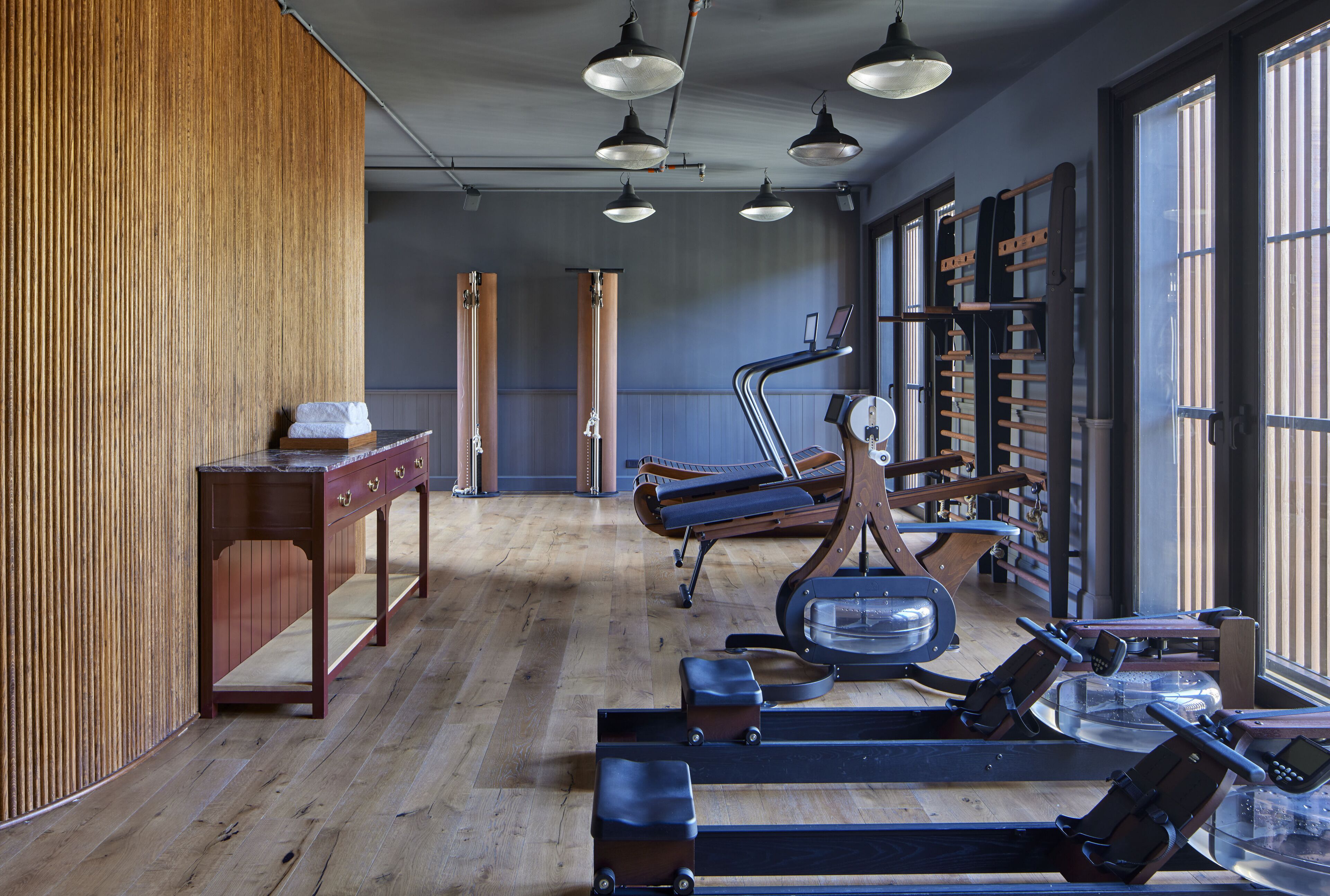 A gym with exercise equipment, wooden walls, and large windows.