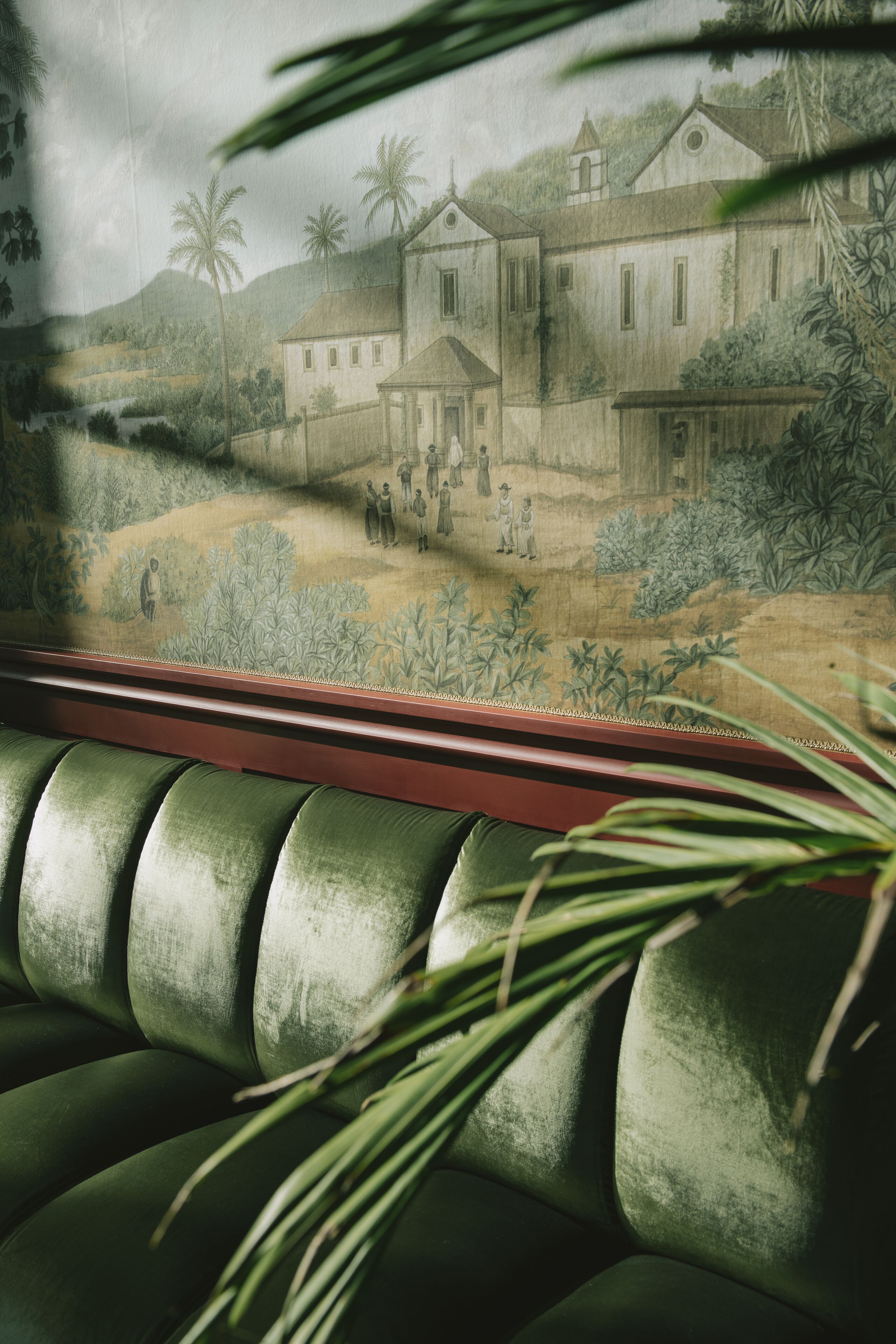 A mural depicting a colonial-style building with palm trees and a group of people in the foreground.