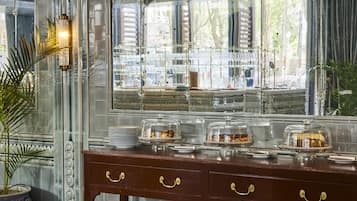 Un buffet aménagé avec un mur recouvert de carreaux de marbre, un élément décoratif mural et un buffet en bois doté de plateaux en verre.