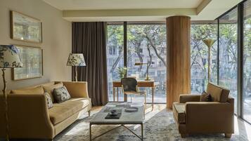 Un salon moderne avec un canapé, des fauteuils, une table basse et une vue sur le paysage urbain grâce à de grandes fenêtres.