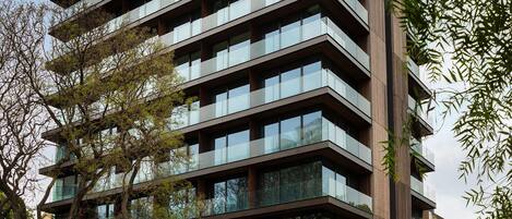 A multi-story building with a modern architectural design, featuring a combination of glass and wooden facade elements.