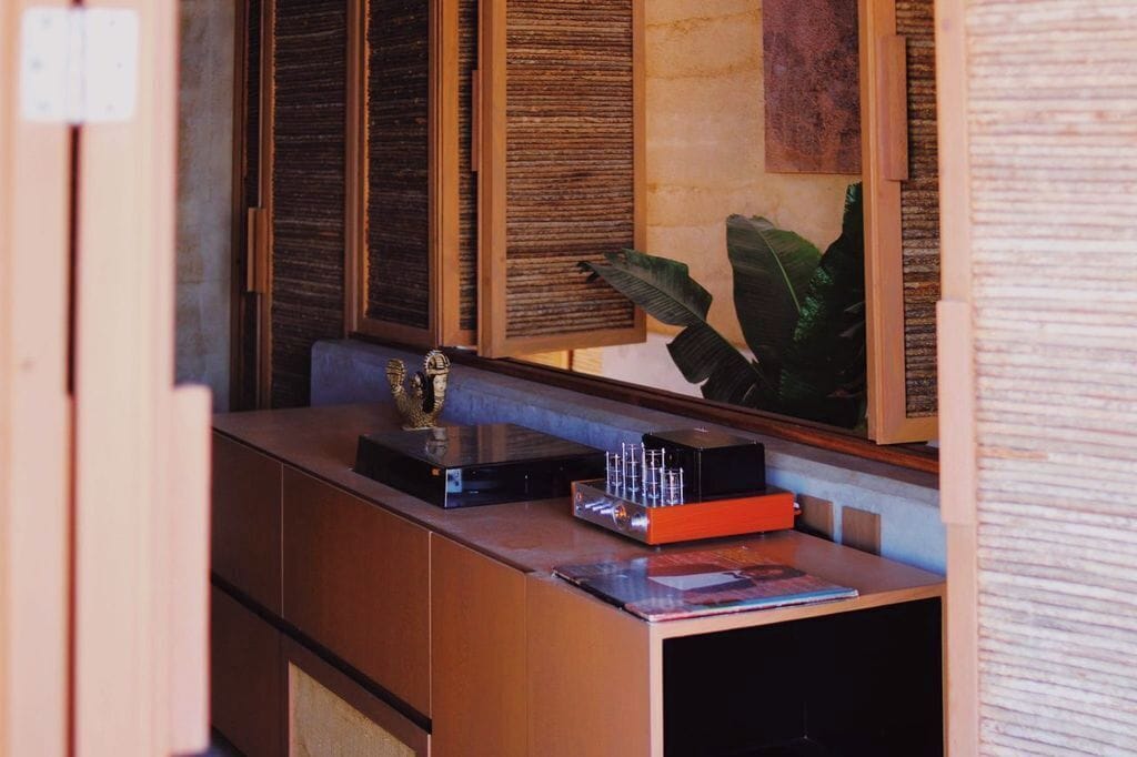 Un mostrador de recepción con detalles de madera, una planta y un espejo que refleja la habitación.