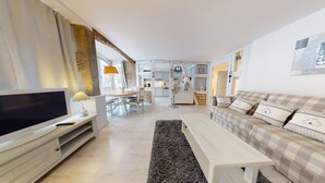 Ein modernes Wohnzimmer mit Fernseher, Sofa und Essbereich.