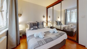 Ein Hotelzimmer mit einem großen Bett, zwei Nachttischen, einem Spiegel und einem Fenster mit Vorhängen.