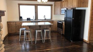 A kitchen with wooden cabinets, a black refrigerator, a stove, and a large window.