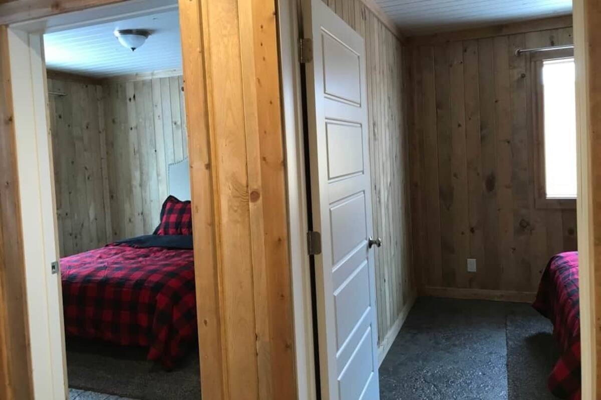 Une pièce aux murs lambrissés, avec un lit et une porte.