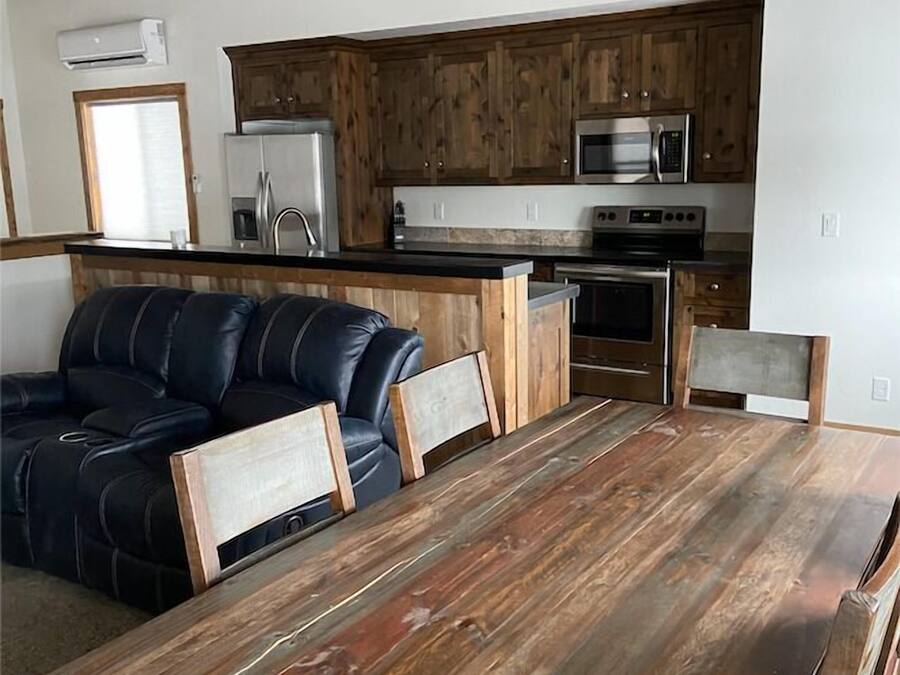 Een moderne keuken met houten kastjes, roestvrijstalen apparatuur en een zwarte leren bank.