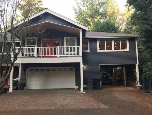 Ein zweistöckiges Haus mit Garage, Balkon und einem umzäunten Garten.