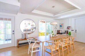 Een lichte keuken met een ronde spiegel, een houten eettafel en stoelen.