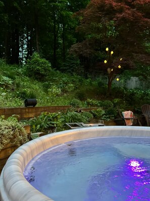 Ein Whirlpool, umgeben von üppigem Grün und einer Holzterrasse.