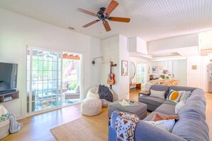 A spacious living room with a grey sofa, a television, and a ceiling fan. - Private Hot Tub • Fenced Yard • Dog-Friendly Wine Country Retreat (Fennville)