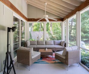 A covered outdoor seating area with a ceiling fan, wicker furniture, and a view of greenery. - Dog Friendly • Hot Tub • Firepit • Wine Country (Fennville)