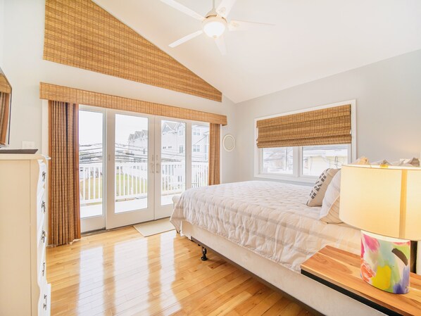 Quarto com cama, ventilador de teto e vista para o exterior.