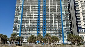 Un hotel de gran altura con varios pisos, balcones y una llamativa franja azul que recorre verticalmente el centro.
