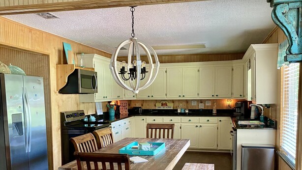 A kitchen with wooden cabinets, a stainless steel refrigerator, a microwave, a stove, and a dining table with chairs. - fishing ~ plenty of parking ~ 1/2 mile to marina ~ 5 min to new WestBay casino (Mead)