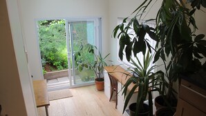 A room with a wooden floor, a table, chairs, and several potted plants. - Gorgeous two story private home and garden 1/2 a block from McGolrick Park  (Brooklyn)