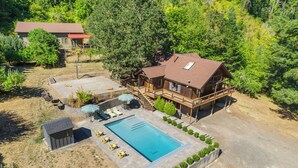 Une grande maison avec une piscine, une terrasse et un petit abri de jardin.