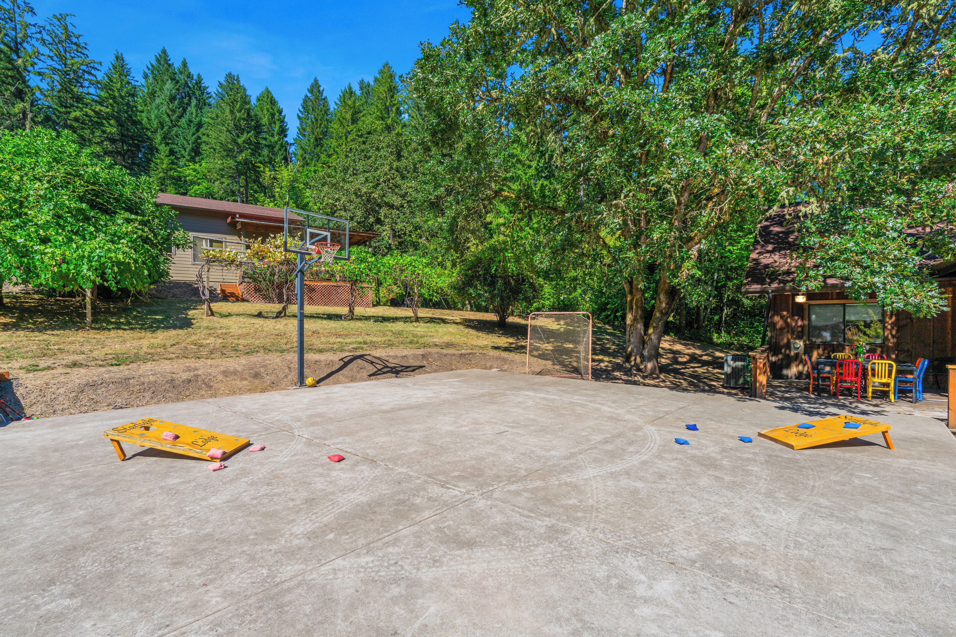 En støbt terrasse med shuffleboard-borde, en basketballkurv og en mindre bygning i baggrunden.