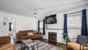 Ein modernes Wohnzimmer mit Kamin, einem Wand-Fernseher und einer Couch.
