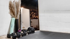 Ein Fitnessbereich mit Trainingsgeräten, einer Yogamatte und einer Zierpflanze.